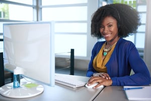 Portrait of a smiling customer service representative with an afro at the computer using headset